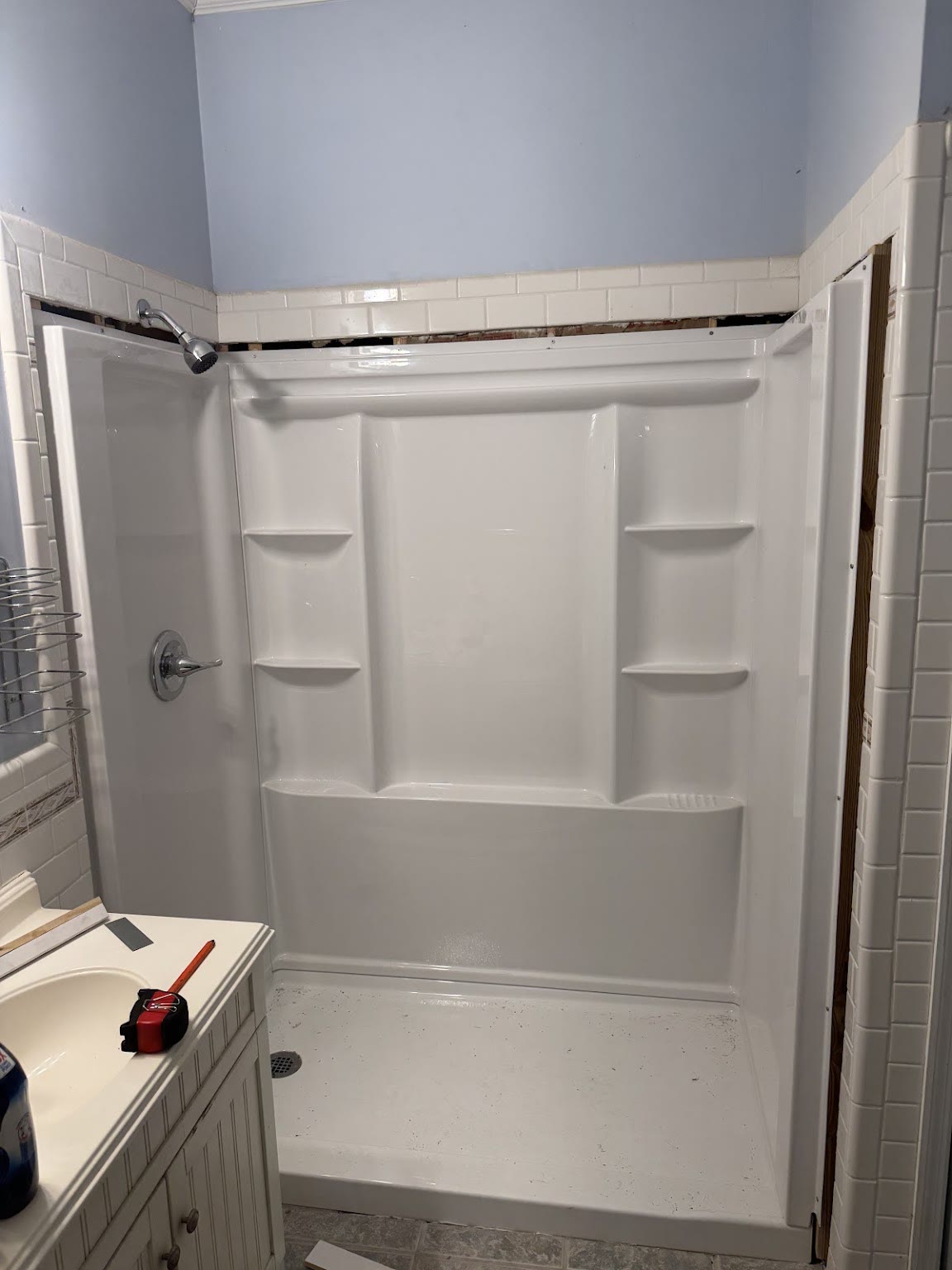 A newly installed shower surround with subway tile above it.