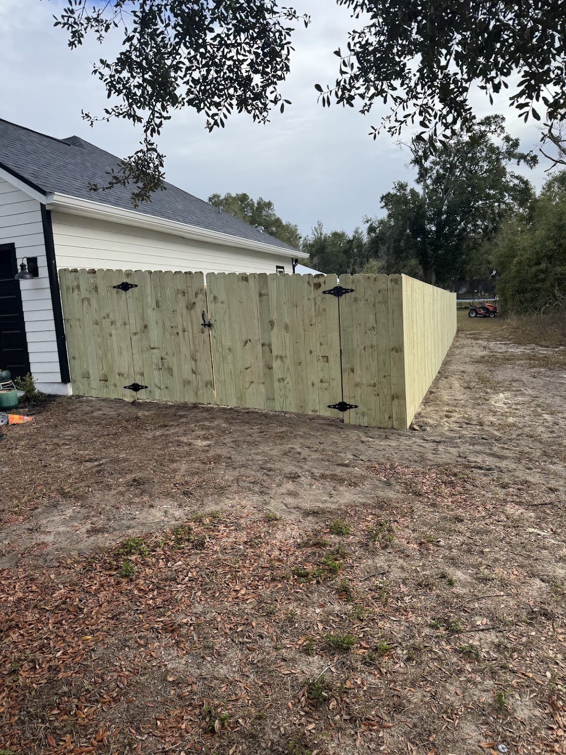 A new wood privacy fence with arched gate panels running along the side of a home.