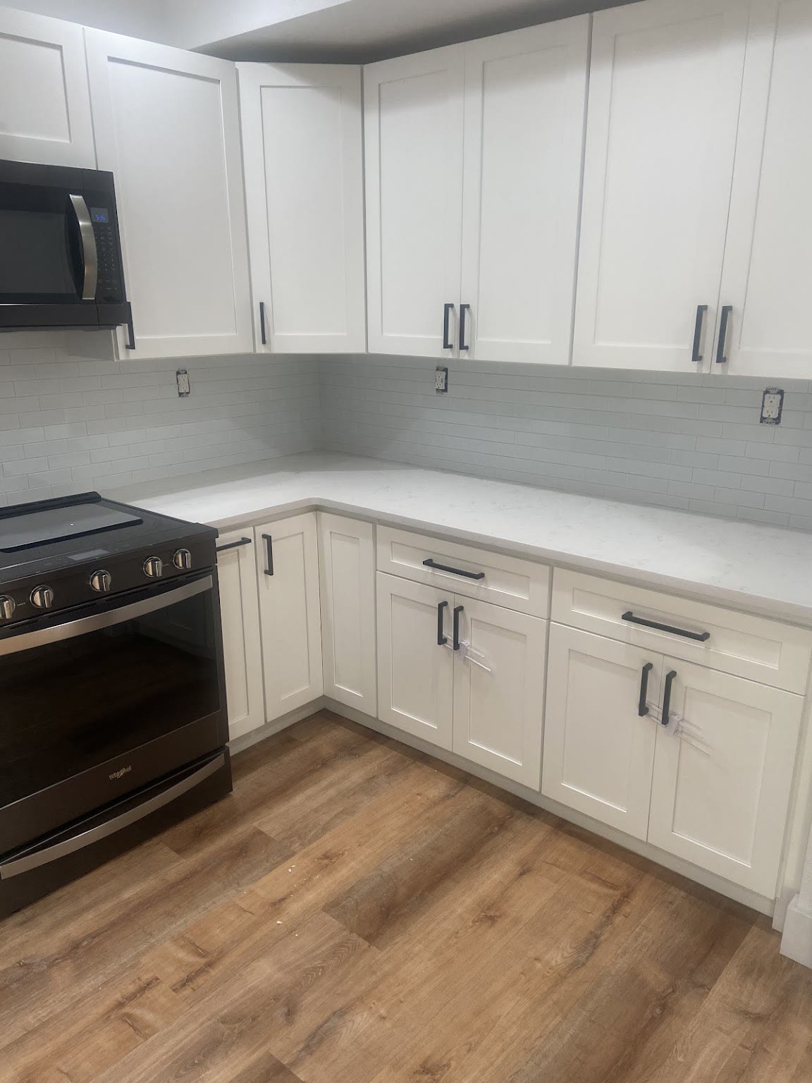 White shaker cabinets, quartz countertops and a new range in a finished kitchen.